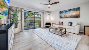 A modern living room with a sofa, coffee table, and a ceiling fan. - Kihei Garden Estates Condo | Pool, Hot Tub, Ground Floor, AC, Walk to Beach (Kihei)