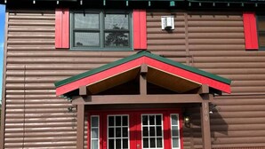 A two-story log cabin with a red front door, a green roof, and a chimney. - The Red Bears Den / Walk to River & Lake, In Town (Grand Lake)