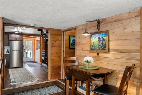 Un intérieur en bois comprenant un coin repas, un réfrigérateur et un tableau accroché au mur.