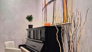 Ein Klavier mit schwarzem Finish, ein weißer Stuhl und eine Vase mit Zweigen.