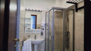 Ein Badezimmer mit Duschkabine, Waschbecken und Spiegel.