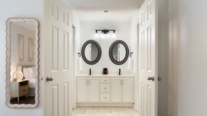 Une salle de bain avec deux miroirs ronds, un meuble-lavabo avec des tiroirs et un luminaire placé au-dessus des miroirs.