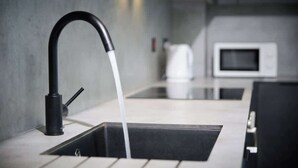 A modern kitchen with a sleek black faucet, a stainless steel sink, and a white microwave. - M16 Urban Green (Manchester)
