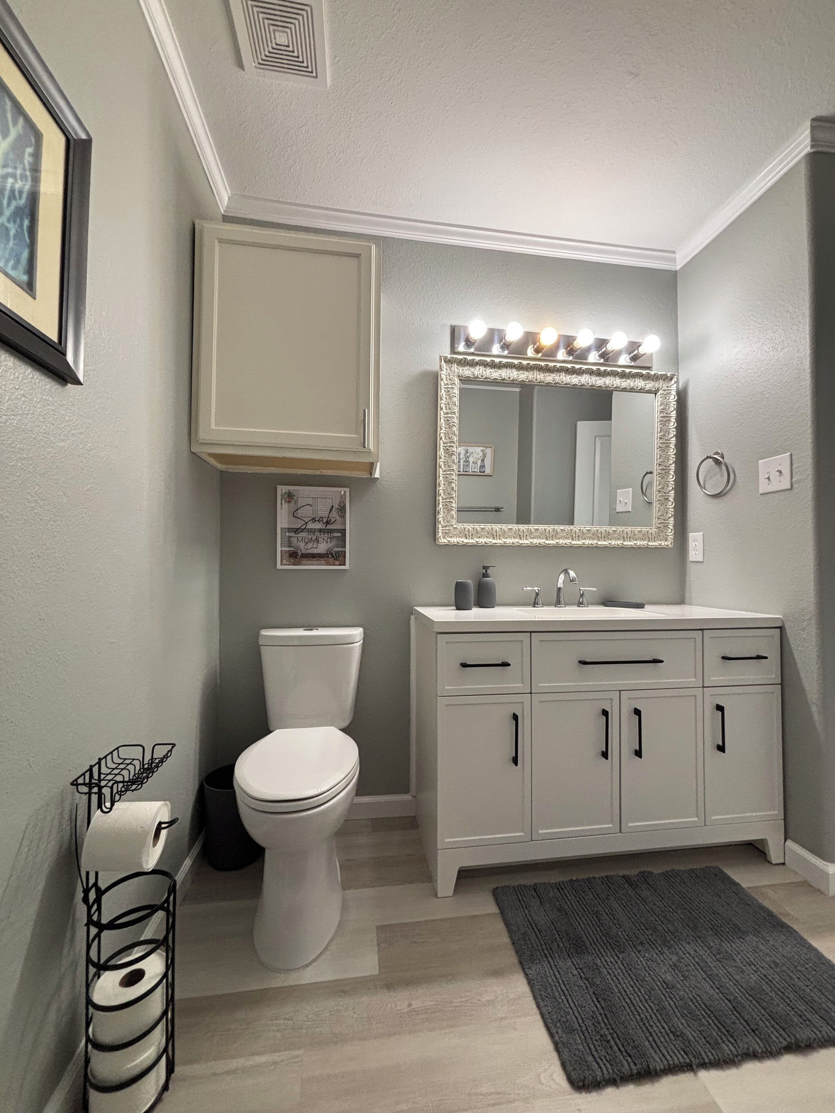 Een badkamer met toilet, wastafel en een verlichte spiegel.