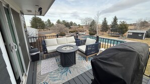 Eine überdachte Terrasse mit einer Couch, einem kleinen Tisch und einem Grill.