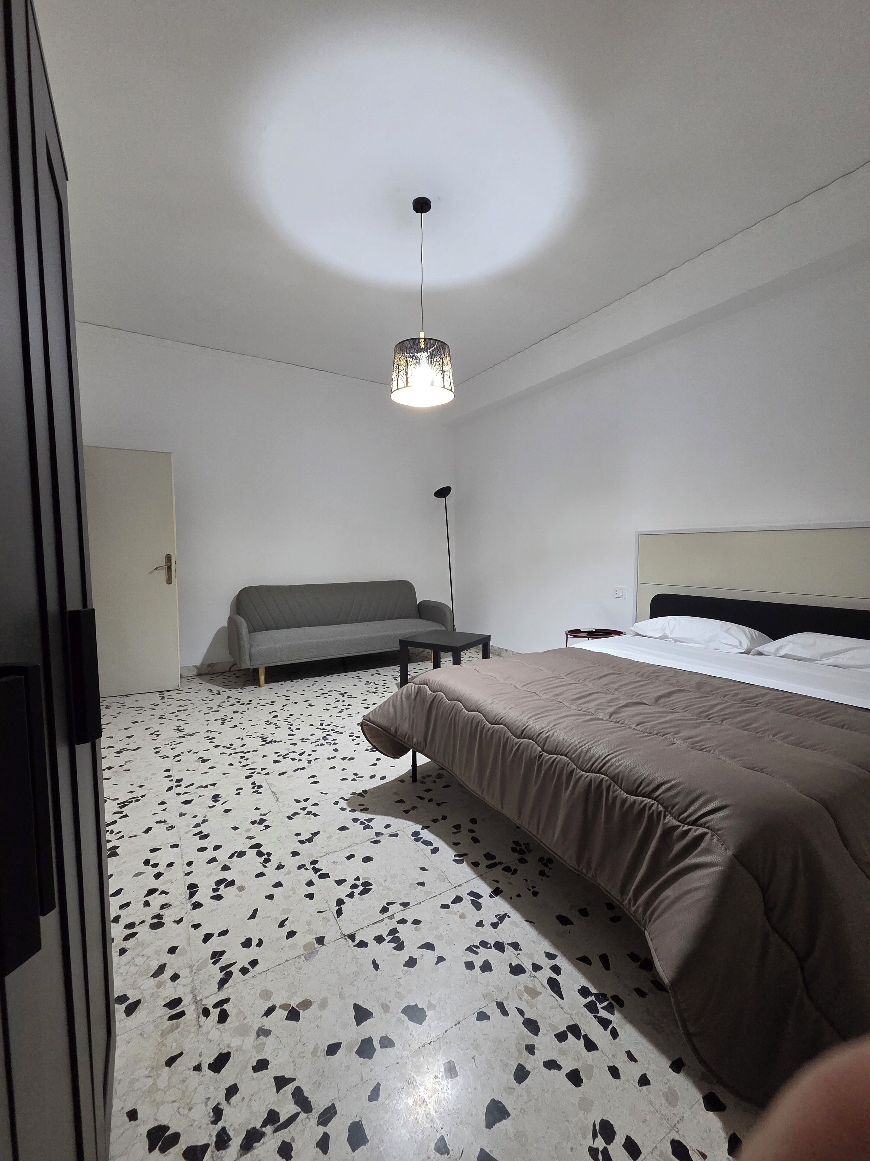 Une chambre à coucher comprenant un lit, un canapé, une petite table et une lampe sur pied.