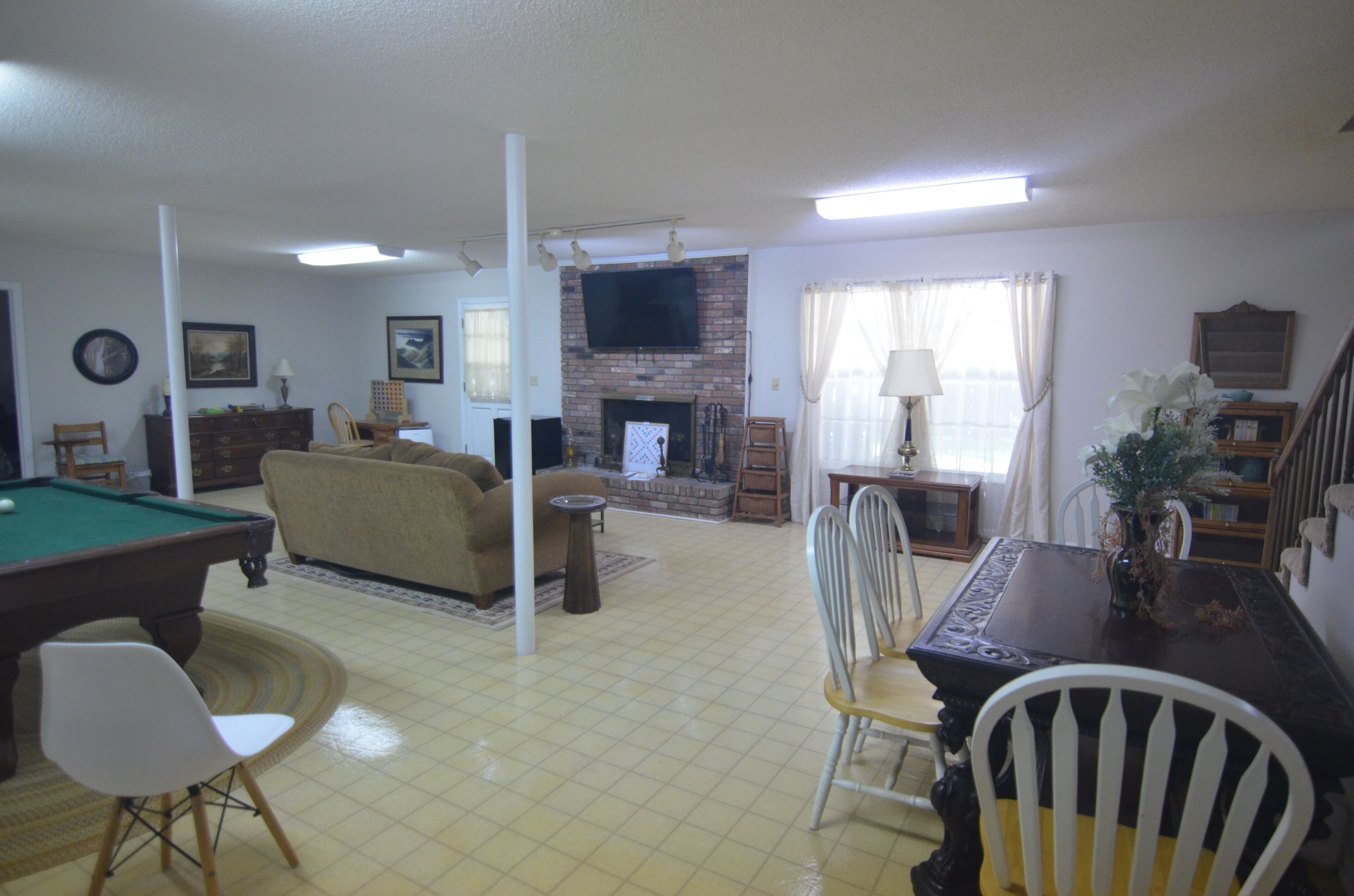 A living room with a pool table, a sofa, a fireplace, and a dining area with chairs.