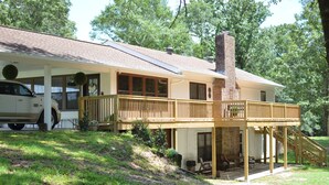 A two-story house with a covered porch, a brick chimney, and a car parked in the driveway.