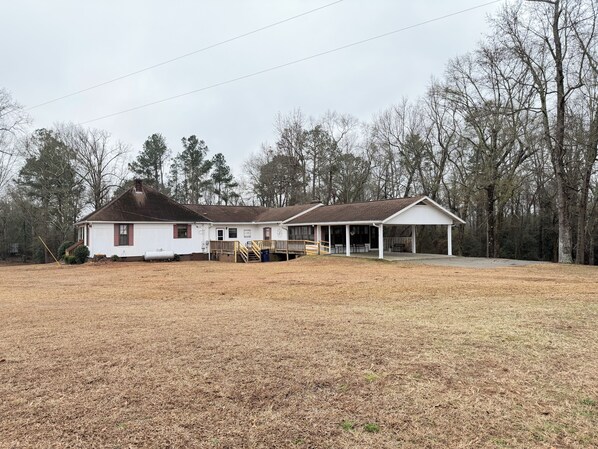 A white two-story house with a covered porch and a fenced yard.