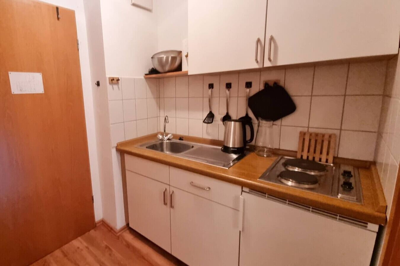 Een kleine keuken met een spoelbak, fornuis en kastjes.
