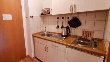 Een kleine keuken met een spoelbak, fornuis en kastjes.