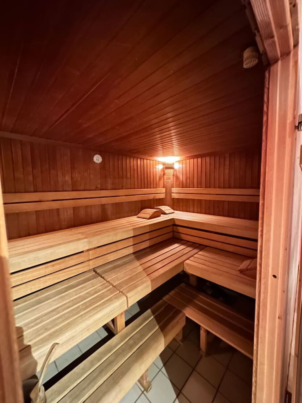 Una sauna de madera con bancos y un calentador fijado a la pared.