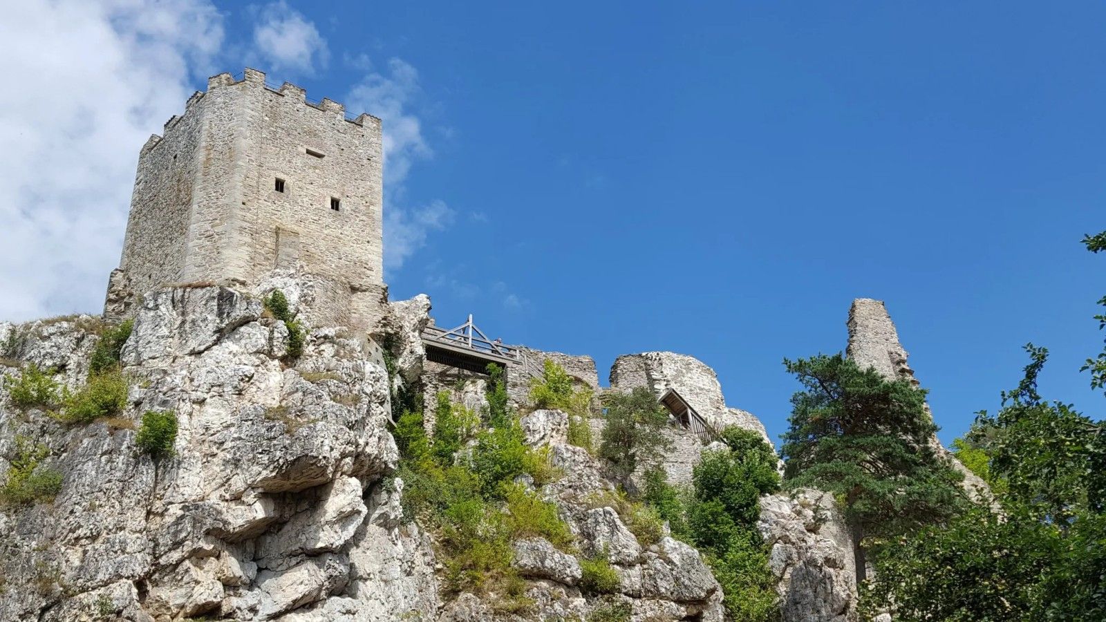 Un castillo de piedra histórico alzado sobre un acantilado rocoso bajo un cielo despejado.
