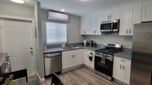Una cocina moderna con armarios blancos, electrodomésticos de acero inoxidable y horno empotrado.