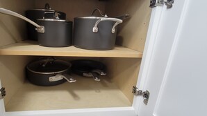 Un armario de cocina con tres ollas negras en el estante superior y una en el inferior.