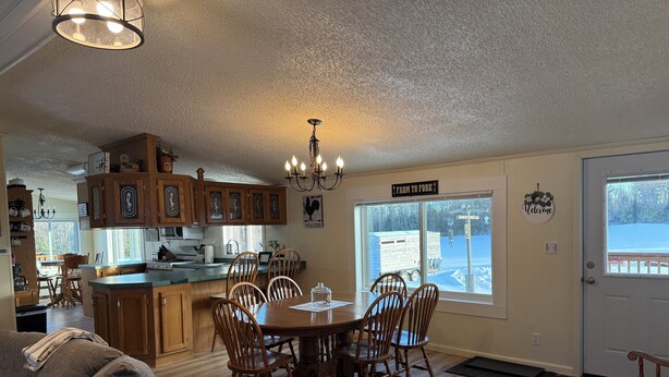 A cozy kitchen with wooden cabinets, a dining table with chairs, and a chandelier.