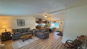 A living room with a sofa, coffee table, and a dining area with chairs and a table.
