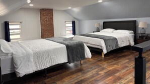 A bedroom with two beds, a brick wall, and wooden flooring. - Blue Getaway (Gettysburg)