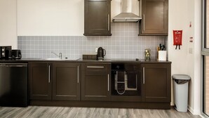 A modern kitchen with dark cabinets, a stainless steel range hood, a built-in oven, and a dishwasher. - Luxury Cinema Lounge 2Bed Leeds City Centre FREE Parking (Leeds)