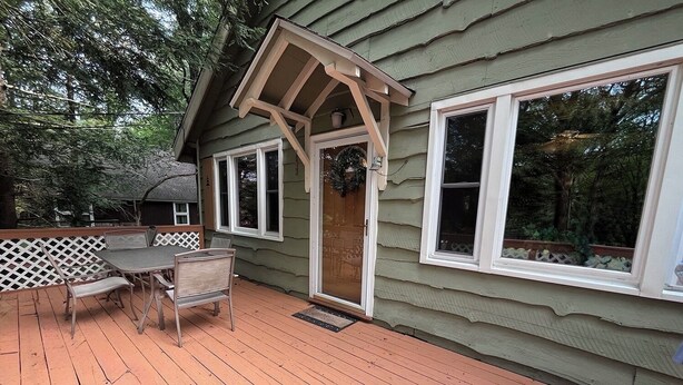 Eine Holzterrasse mit Tisch und Stühlen, ein überdachter Patio-Bereich und große Fenster.