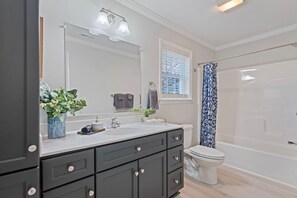 A modern bathroom with a large mirror, a sink, a toilet, and a shower area. - Blue Ridge Haven-Stylish, Views, Central Location! (Maggie Valley)