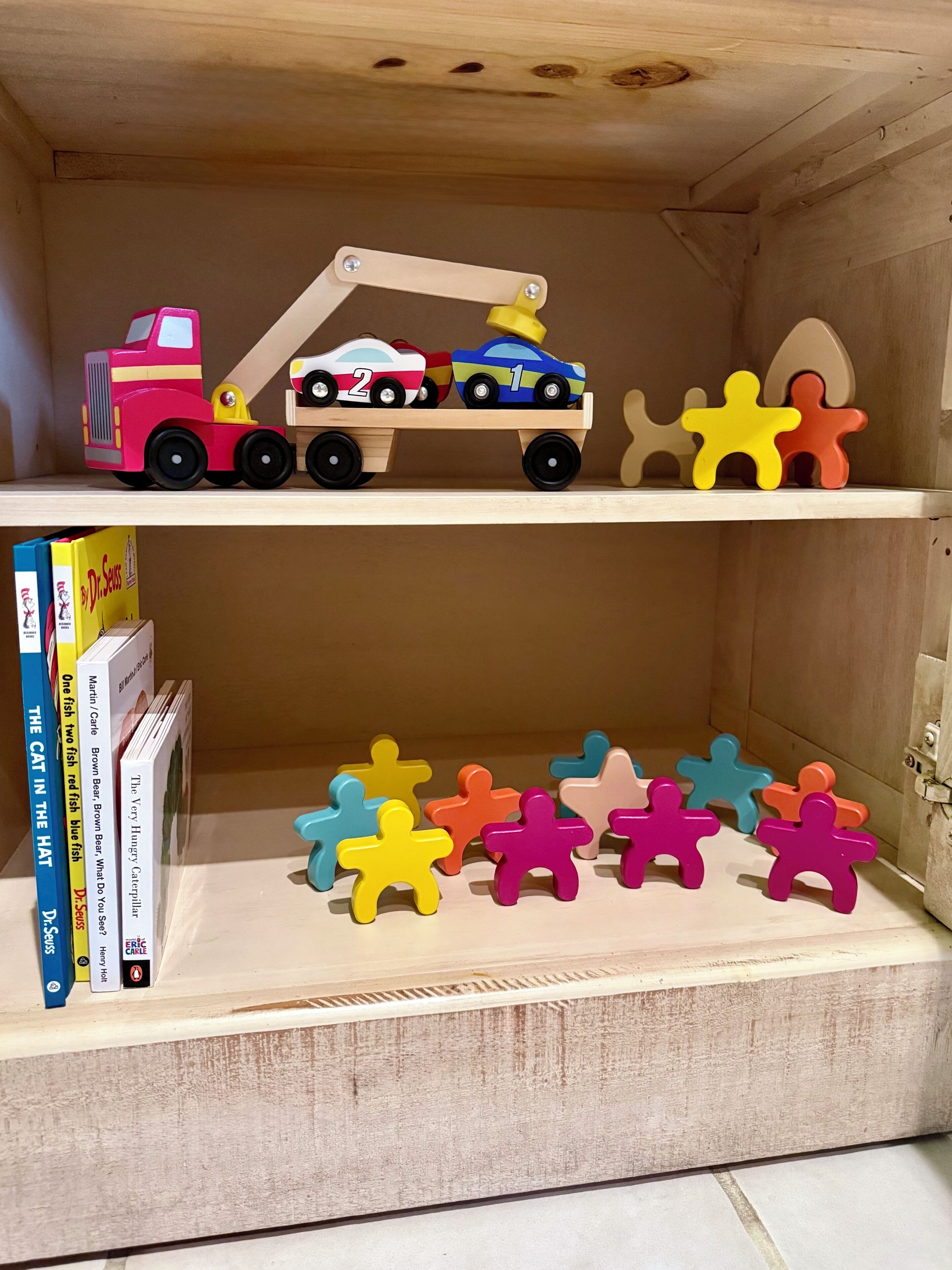 A wooden shelf with a toy tow truck and colorful puzzle pieces.