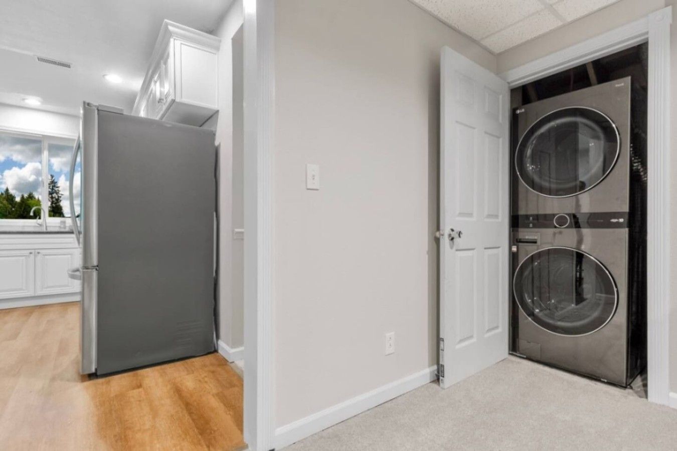A laundry room with a washer and dryer, a gray refrigerator, and a white door.