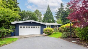 A single-story building with a garage, surrounded by lush greenery and trees. - Spacious 6BR/4BA | Close to Airport @South Seattle (Tukwila)