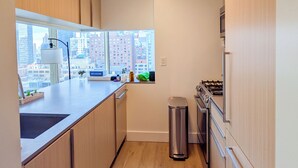 Una cucina moderna con mobili in legno, un cestino in acciaio inossidabile e una finestra con vista sulla città.