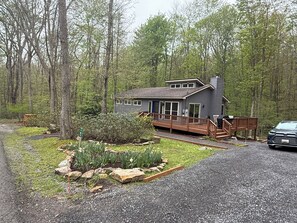 Eine Hütte mit einer Terrasse, umgeben von einem Wald.