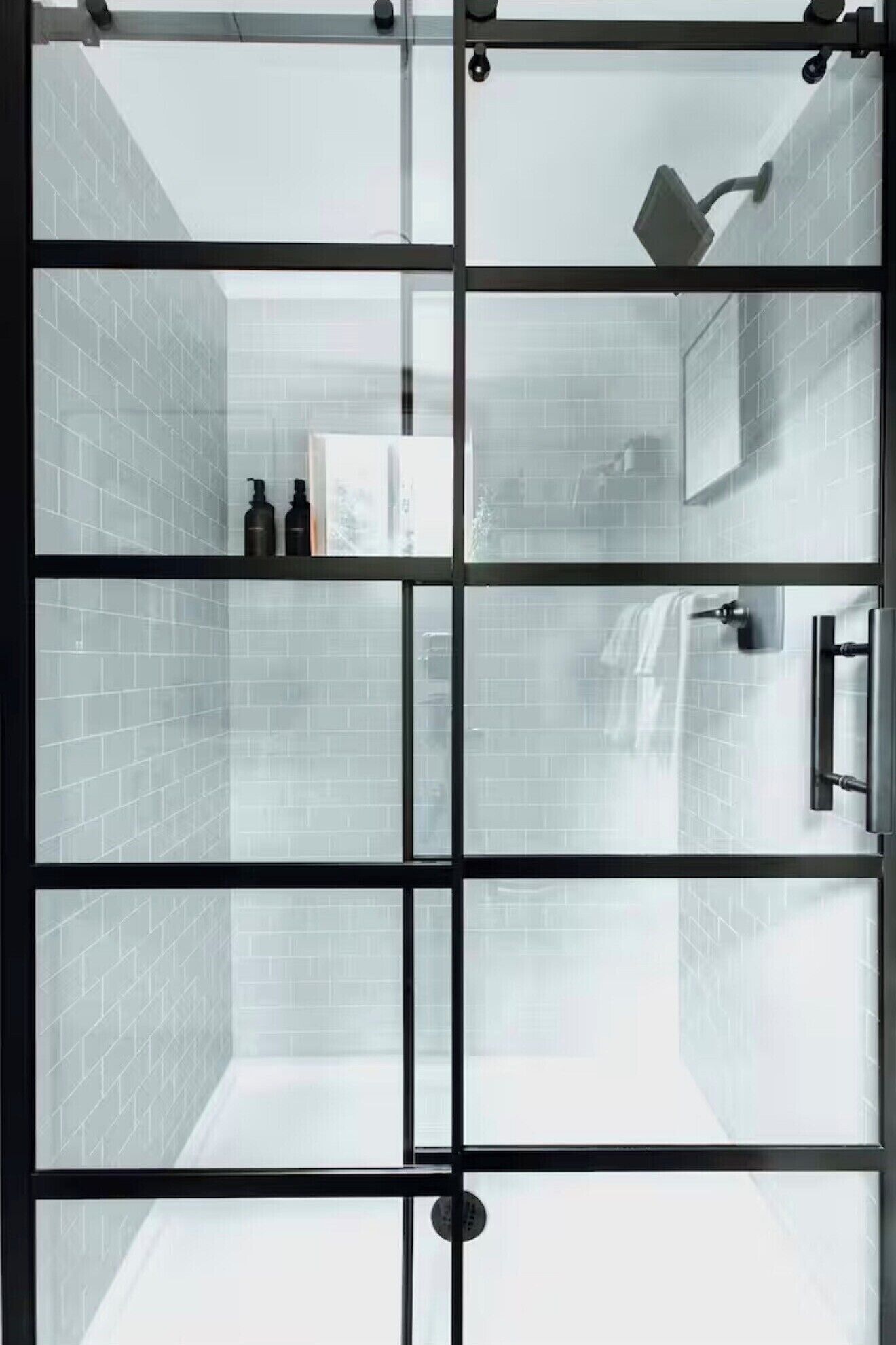 A modern bathroom with a glass partition, a shower area, and a shelf with toiletries.