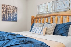 Ein Bett mit einem hölzernen Kopfteil, mehreren Kissen und einer blauen Decke.