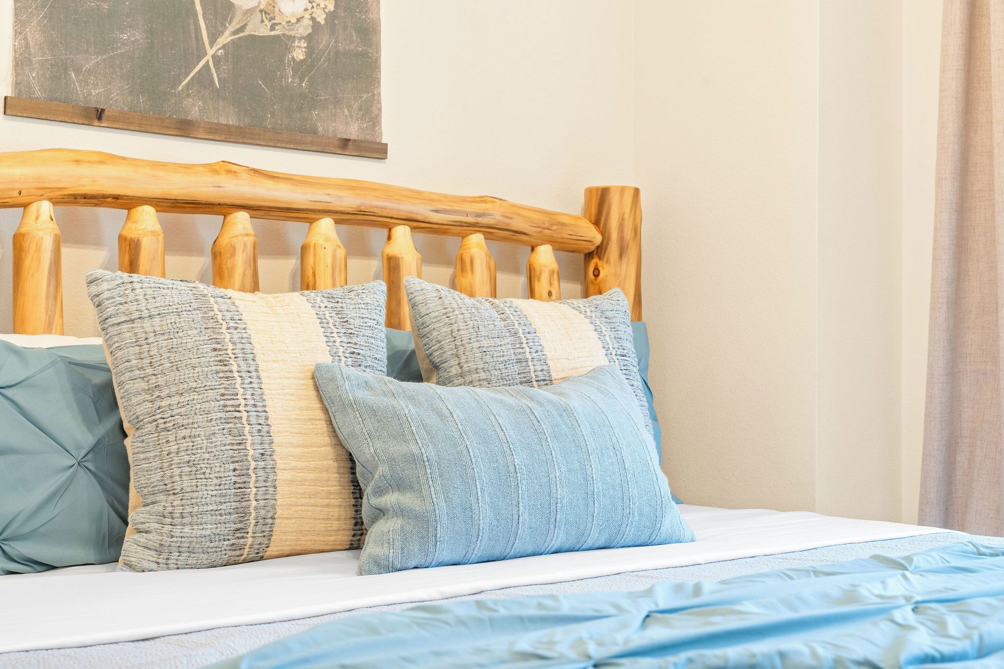 Un lit avec une tête de lit en bois, deux oreillers et une couverture bleue.