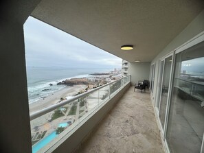 Un balcon avec vue sur la plage et l’océan, une piscine et un espace salon.
