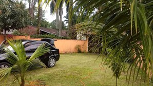 A black car parked in a grassy area with palm trees and a building in the background. - Costa do Sol Condominium, 600m from Guaratuba beach, near Boraceia and Riviera. (Bertioga)