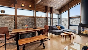A cozy interior with a stone wall, wooden ceiling, large windows, and a fireplace. - Exclusive cabin and annex at the top of Hodlekve (Vestland)