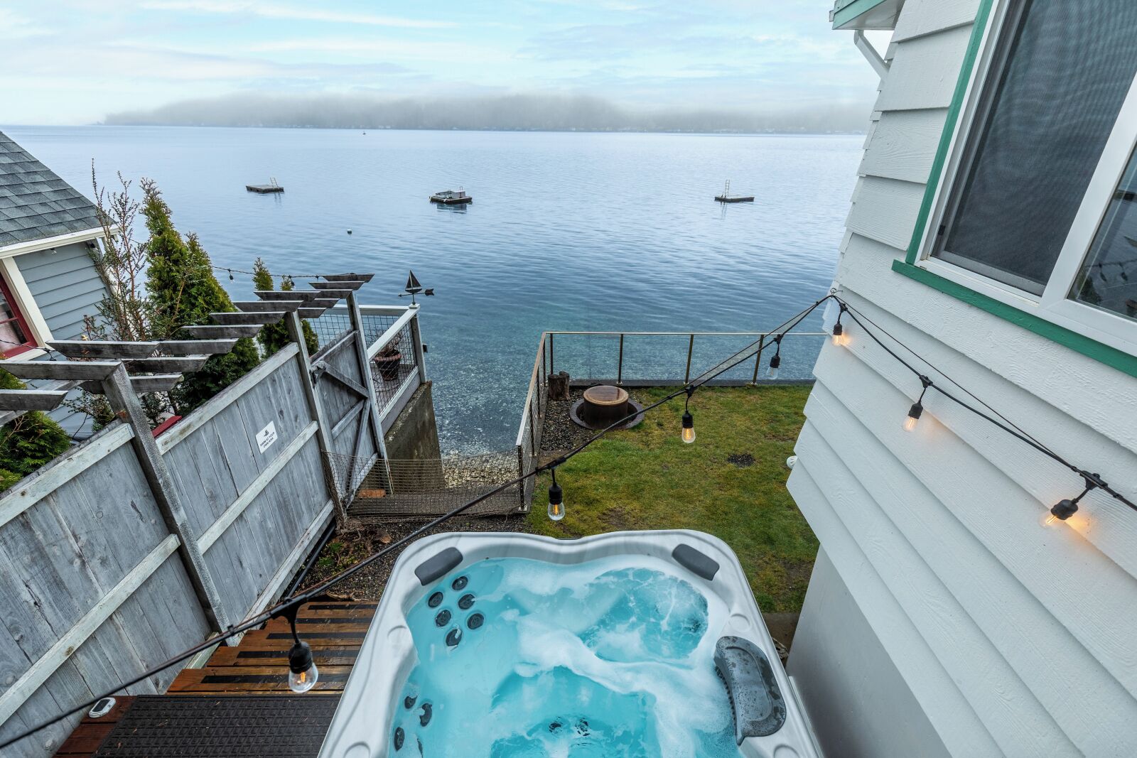 Un jacuzzi en una terraza con vista a un cuerpo de agua y barcos.