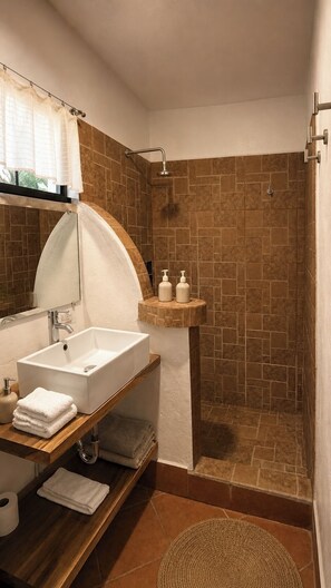 Un bagno con un lavandino bianco, uno specchio, una doccia e un portasciugamani.