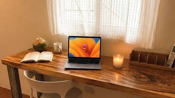 Un escritorio de madera con una computadora portátil, un libro abierto, una vela y un adorno.