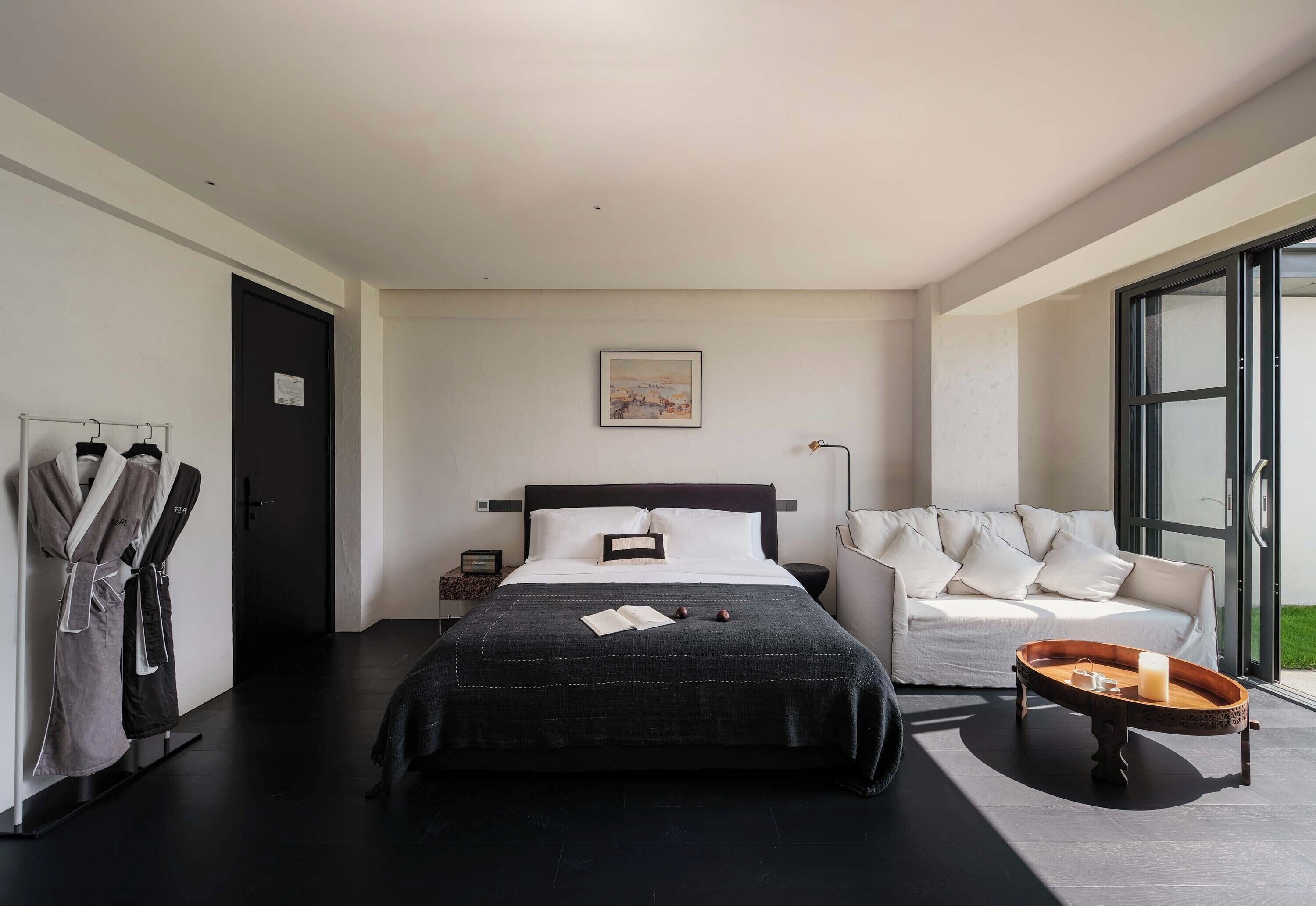 Un dormitorio moderno con una cama grande, una mesita de noche, un sofá y una ventana.