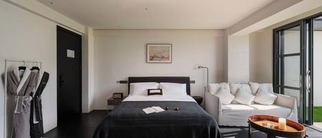 Un dormitorio moderno con una cama grande, una mesita de noche, un sofá y una ventana.