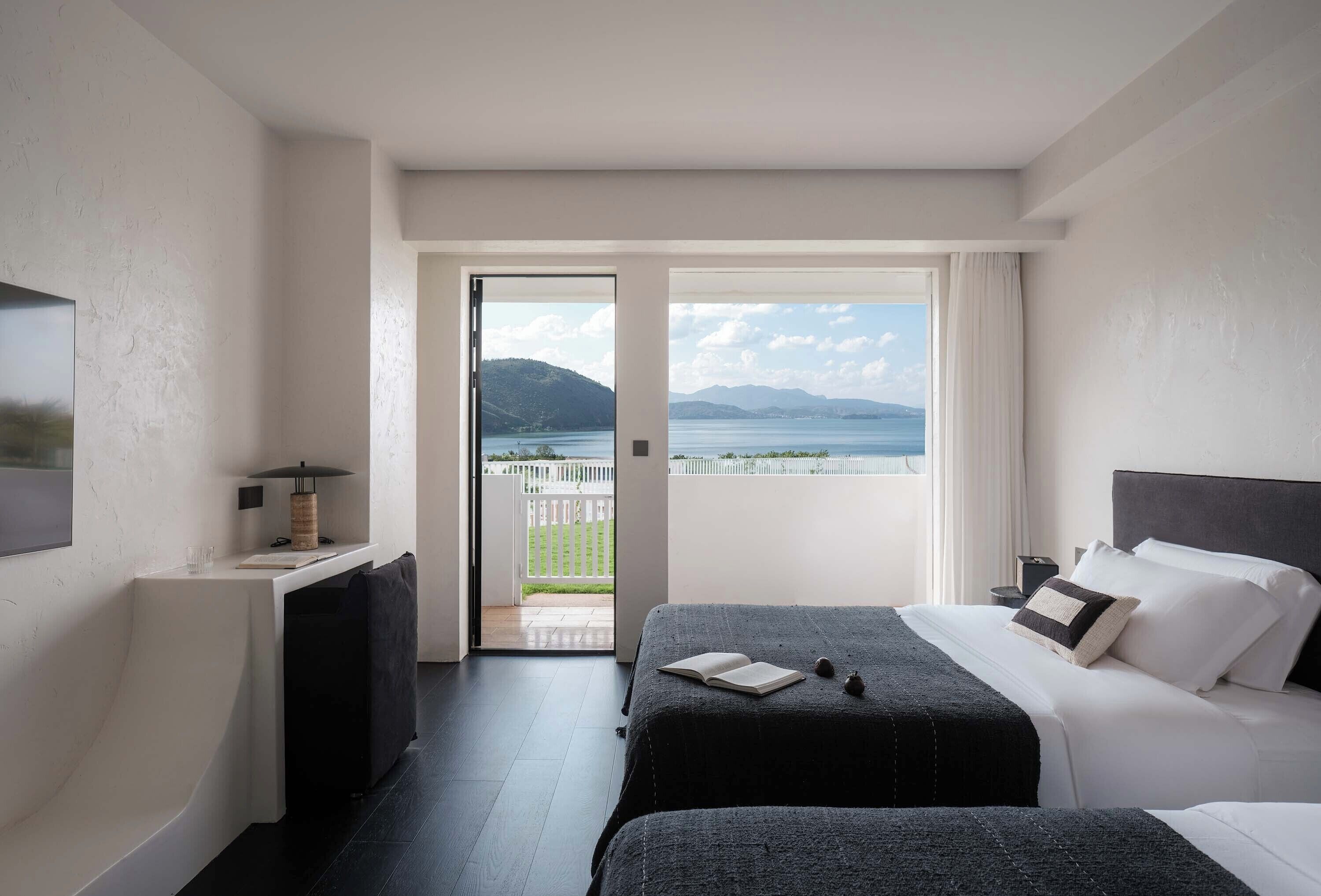Una habitación de hotel con cama, escritorio y vista al mar.