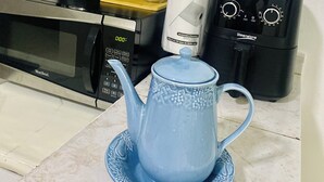 Una cocina con microondas, cafetera y hervidor en la encimera.