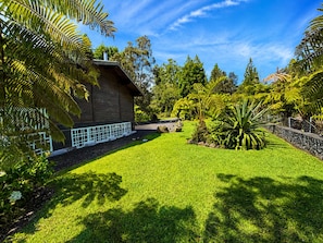 A well-maintained garden with a wooden building, lush greenery, and a clear sky.