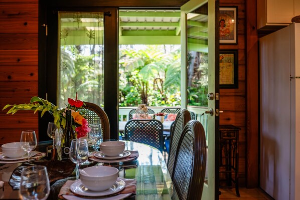 A dining area with a table set for two, featuring a bottle of wine, glasses, and a vase with flowers.