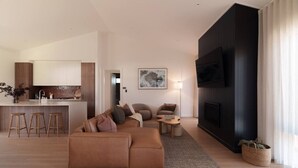 Ein modernes Wohnzimmer mit einem braunen Sofa, einem Couchtisch und einem an einer dunkelgrauen Wand montierten Fernseher.