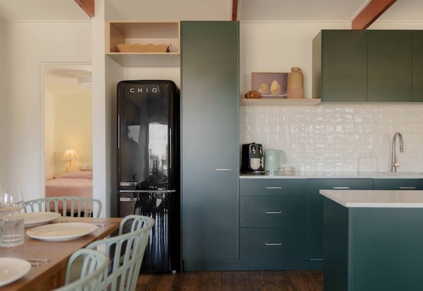 A compact kitchen with a built-in refrigerator, a dining area with a table and chairs, and a kitchenette with cabinets and a sink.