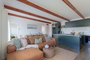 Una sala de estar moderna con un sofá, una mesa de centro y una zona de cocina con mostrador y armarios.