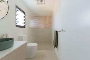 A modern bathroom with a large sink, toilet, and shower area.