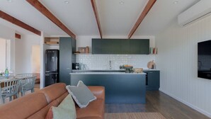 A modern kitchen with a central island, dark green cabinets, and a built-in oven. - Soul Shack ~ 6 bedroom Soulful Coastal Escape (Aldinga Beach)